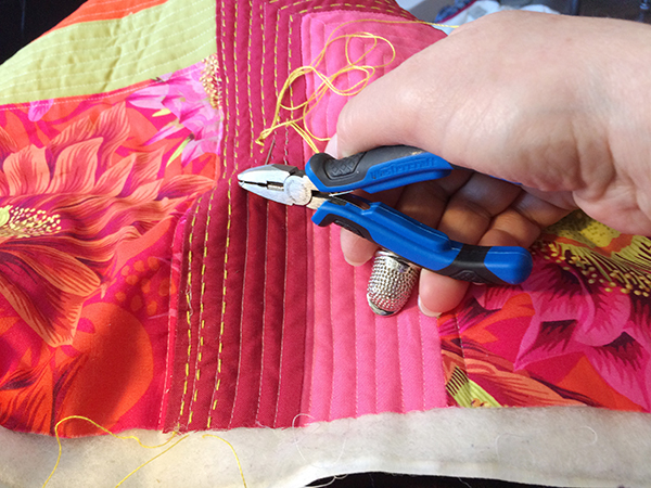 Using pliers to push needle through quilt